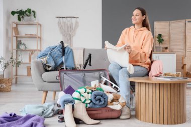 Kadın turist sıcak giysilerini bavuluna koyuyor.