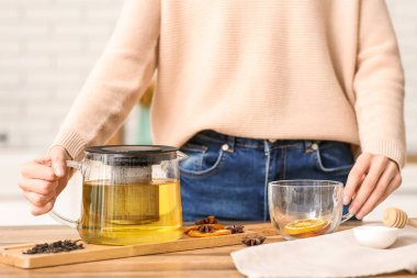 Genç bayan mutfakta baharatlı yeşil çay yapıyor.