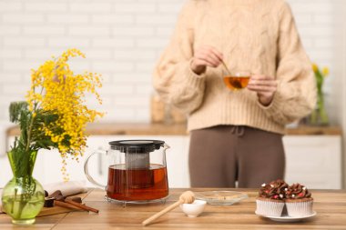 Mutfakta siyah çay karıştıran genç bir kadın.