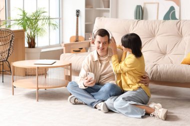 Kulaklığa ve cep telefonuna aşık genç bir çift evde oturuyor.