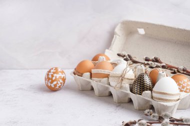 Süslü Paskalya yumurtaları ve beyaz arka planda söğüt dallarıyla kağıt tutucu.