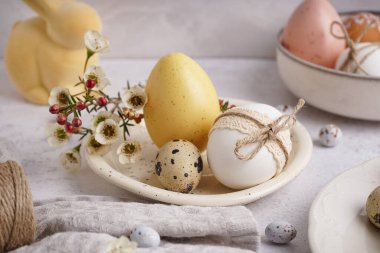 Beyaz arka planda süslü Paskalya yumurtaları ve bahar çiçekleri olan tabaklar