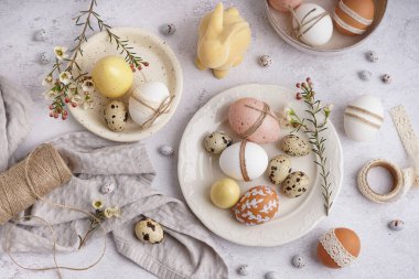 Beyaz arka planda süslü Paskalya yumurtaları ve bahar çiçekleri olan tabaklar