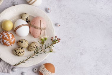 Beyaz arka planda süslü Paskalya yumurtaları ve bahar çiçekleriyle süslenmiş tabak.
