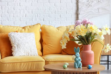 Çiçekli vazo, paskalya yumurtası ve tavşancık oturma odasında sehpanın üstünde, yakın plan.