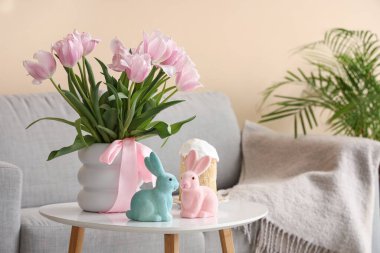 Çiçekli vazo, tavşanlar ve Paskalya pastası oturma odasındaki sehpanın üstünde, yakın plan.
