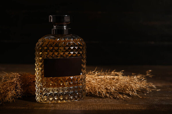 Bottle of modern male perfume on dark wooden background