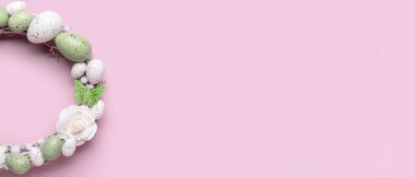 Çiçekli Paskalya çelengi, pembe arka planda yumurtalar ve kelebekler.