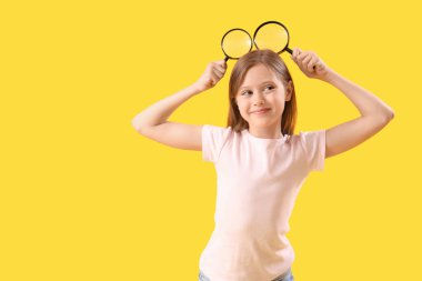 Funny little girl with magnifiers on yellow background clipart