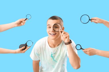 Young man and hands with many magnifiers on blue background clipart