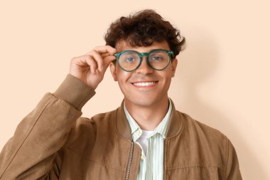 Bej arka planda gözlüklü genç adam, yakın plan.