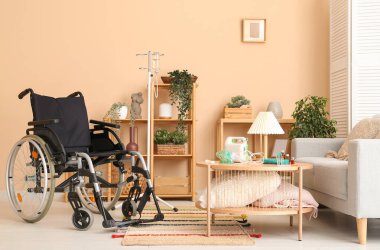 Bej duvarın yanındaki oturma odasında modern boş tekerlekli sandalye.