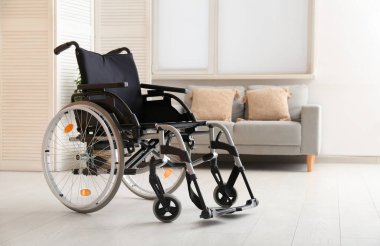 Oturma odasında kanepesi olan modern boş tekerlekli sandalye.