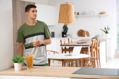 Mutfakta bir bardak meyve suyu olan genç bir adam.
