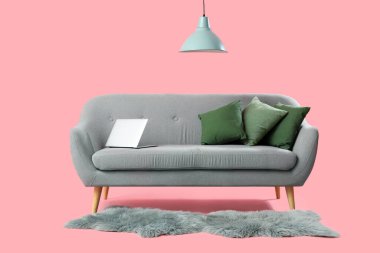 Gri kanepe, dizüstü bilgisayar ve pembe arka planlı modern oturma odası.