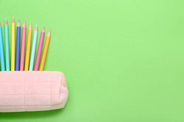 Yeşil arka planda birçok renkli kalemli bir dosya