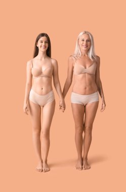 Bej arka planda el ele tutuşan iç çamaşırlı kadın.