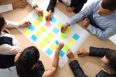 Ofisteki masada yapışkan notlarla çalışan bir grup iş adamı, üst görünüm