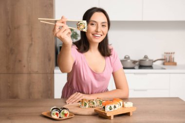 Mutfakta lezzetli suşisi olan mutlu genç bir kadın.