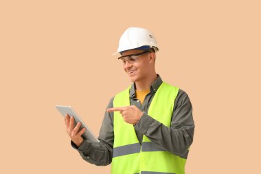 Bej arka planda tablet bilgisayarı olan genç erkek mühendis.