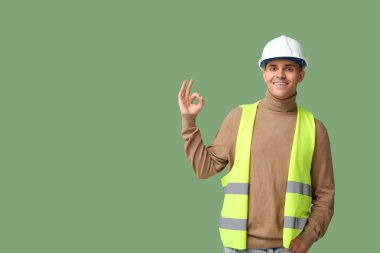 Genç erkek mühendis yeşil arka planda iyi görünüyor.