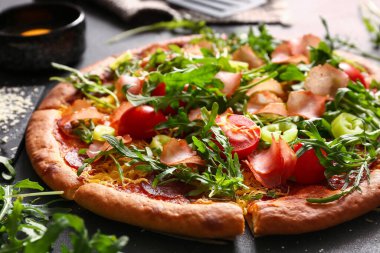 Domatesli lezzetli pizza ve siyah arka planda roka.