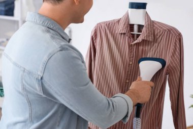 Çamaşır odasında buharlı gömlekli bir adam.