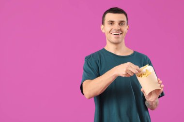 Mor arka planda patates kızartması olan genç adam.