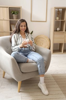 Evde hap okuyan genç bir kadın var.