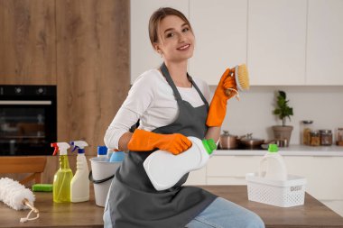 Mutfakta temizlik fırçası ve deterjanı olan kadın hademe.