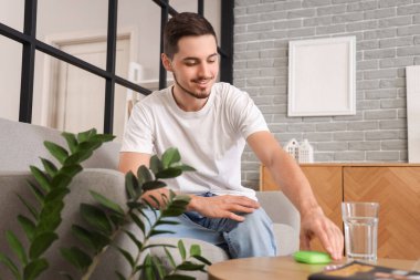 Evde ilaç organizatörü olan genç bir adam var.