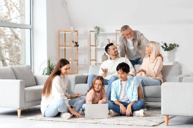 Dizüstü bilgisayarı olan büyük bir aile evde vakit geçiriyor.