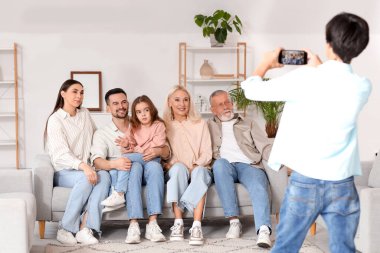 Cep telefonlu küçük bir çocuk büyük ailesinin fotoğrafını çekiyor.