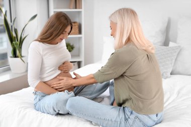 Doğum koçu olan hamile bir kadın yatak odasında oturuyor.