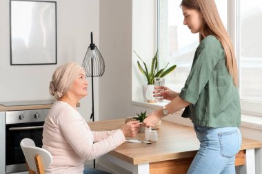 Kemoterapiden sonra olgun bir kadın mutfaktaki kızından hap alıyor. Mide kanseri kavramı