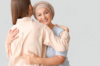 Kemoterapiden sonra olgun bir kadın hafif arka planda kızına sarılıyor. Mide kanseri kavramı