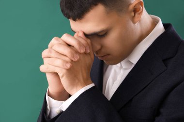 Genç adam yeşil arka planda dua ediyor.