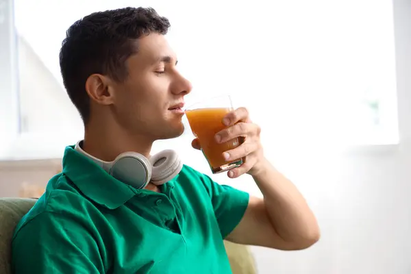 Young man drinking juice at home, closeup
