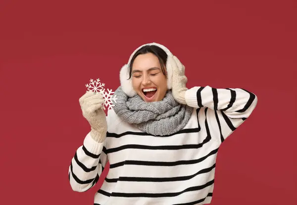 赤い背景に装飾的な雪片を持つ感情的な若い女性 — ストック写真