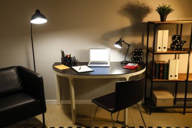 Ofis içi işyeri, boş laptop ve geceleri parlayan lambalar.