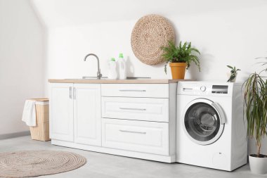 Lavabo, çamaşır makinesi ve çamaşır sepetinin olduğu odanın içi.