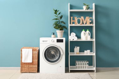 Çamaşır sepeti, çamaşır makinesi ve raf ünitesi olan odanın içi.