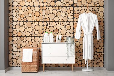 Çamaşır sepetli, tuvaletli ve bornozlu bir oda.