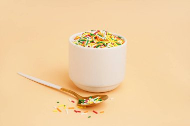 Renkli süslemeli kase ve bej arka planda kaşık.