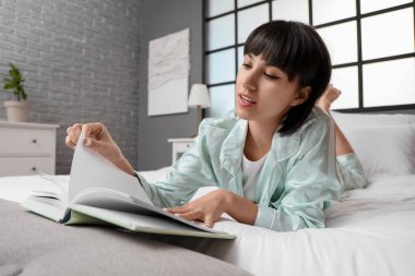 genç kadın evde yatakta kitap okuma