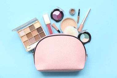 Mavi arka planda farklı makyaj ürünleri olan kozmetik çanta.