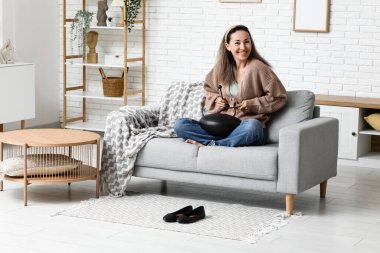 Evdeki kanepede sopayla glukofon çalan mutlu olgun bir kadın.