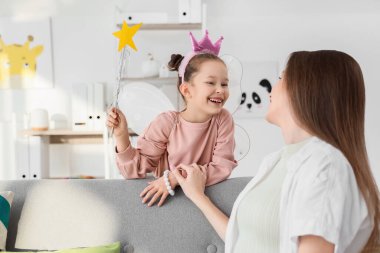 Peri gibi giyinmiş küçük bir kız. Annesiyle evde.