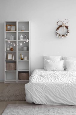 Paskalya çelengi ve raf ünitesiyle aydınlık yatak odasının içinde.