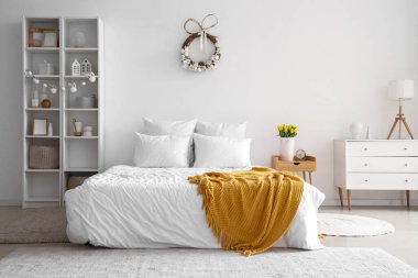 Paskalya çelengi ve raf ünitesiyle aydınlık yatak odasının içinde.